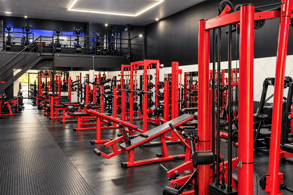 Salão de musculação da Elity Academia com aparelhos vermelhos